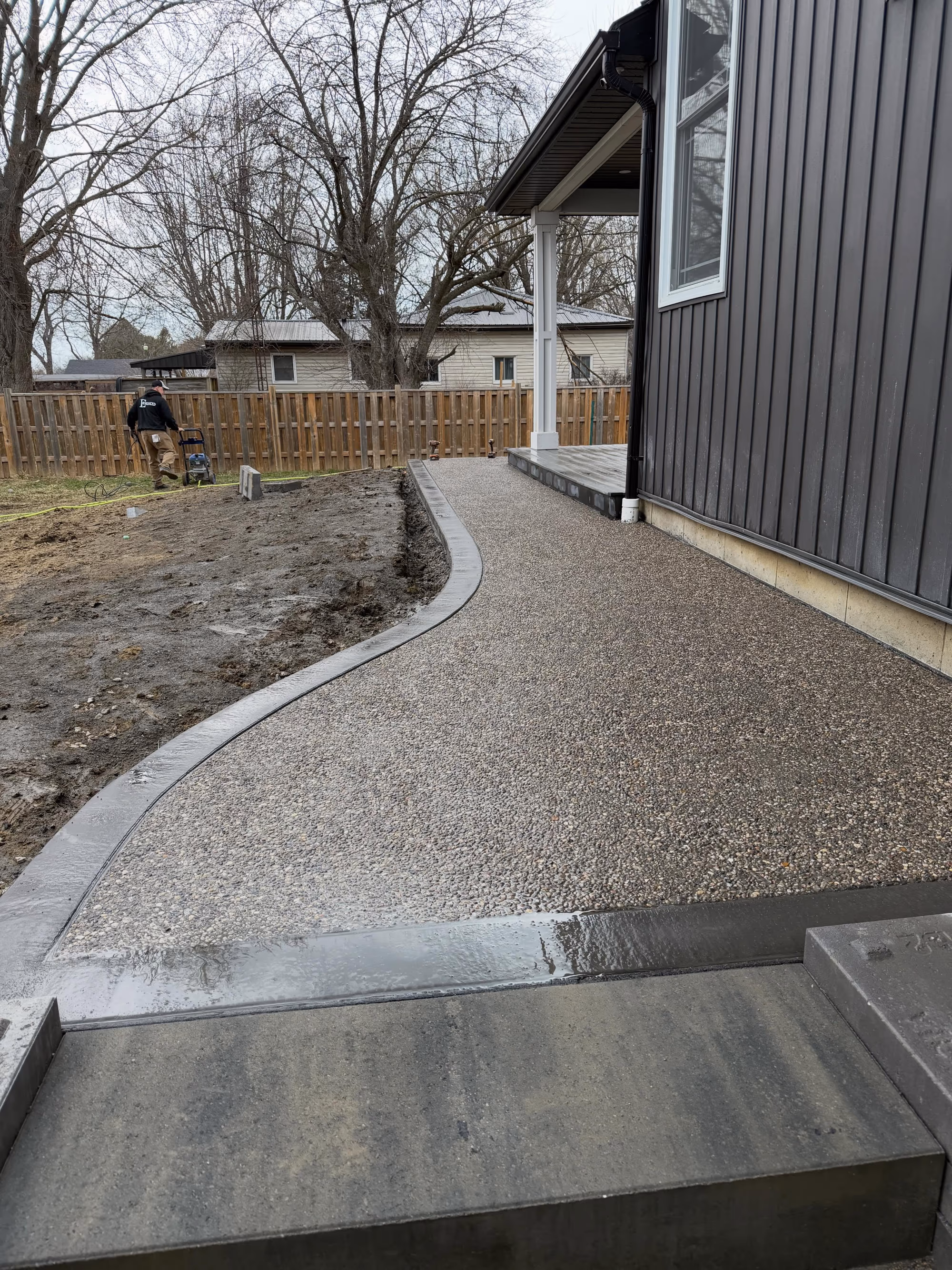 Exposed aggregate concrete walkway with a smooth border beside a home