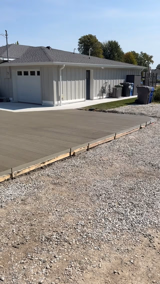 Formed concrete pad beside a detached garage over a compacted gravel base